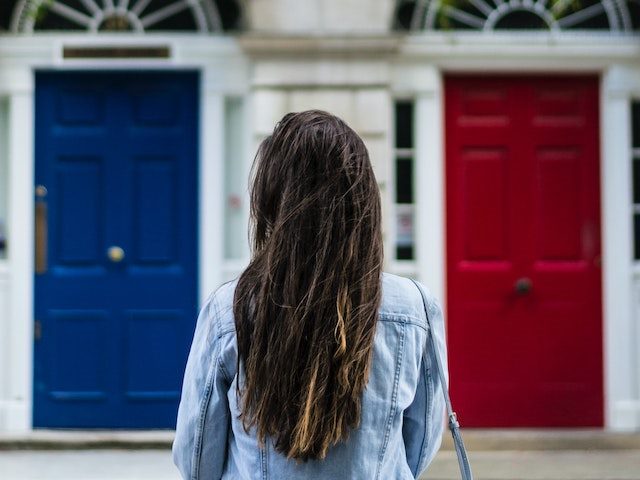 Woman facing a red door and a blue door