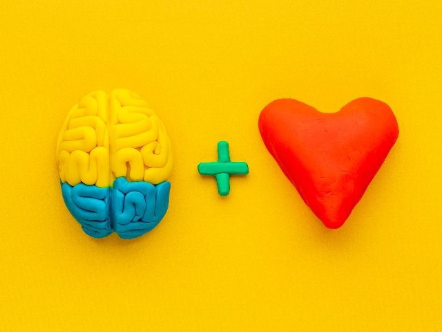 A blue and yellow human brain is on the left, followed by a plus sign, and a red heart is on the right all on a bright yellow background, implying the growing importance of emotionally intelligent AI to brands. 