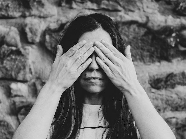 woman covering her eyes in the see no evil pose