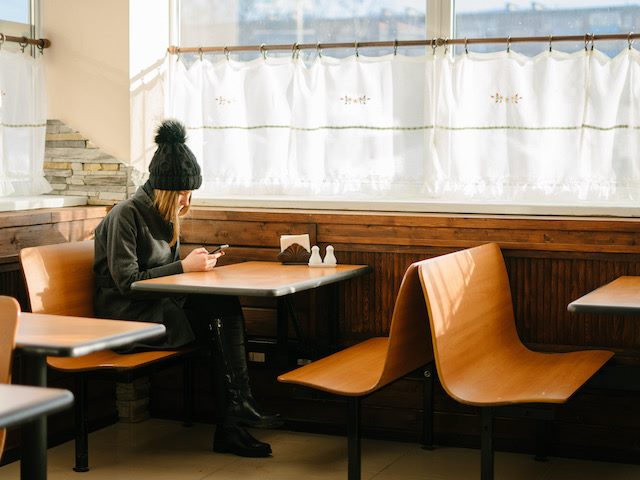 woman looking at her phone while sitting in a diner