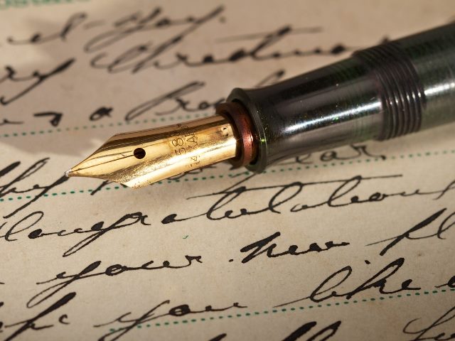 Handwriting on an old discolored vintage postcard and a vintage fountain pen.
