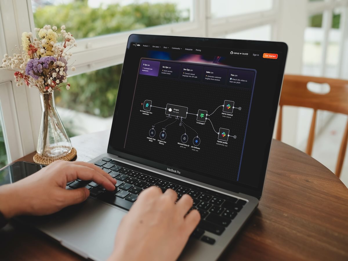  A person uses the n8n workflow automation platform on a laptop, designing a visual flowchart to connect different apps