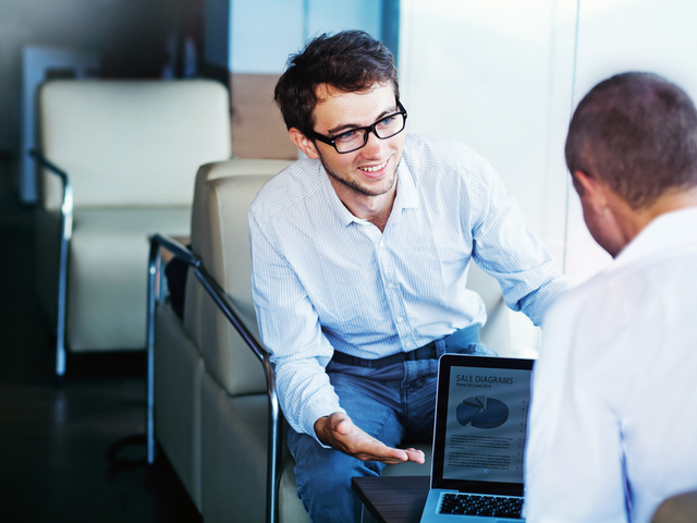 A man sharing information displayed on his tablet, with a coworker.