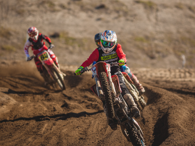 Motorbikes race on a dirt motocross course.