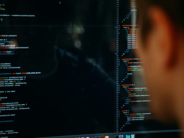 An employee writes software code on a computer.