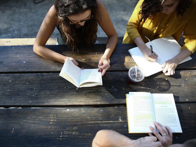 Students study together at a table outside.
