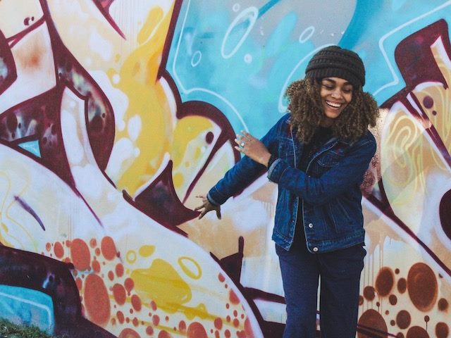 smiling woman  standing in front of street art