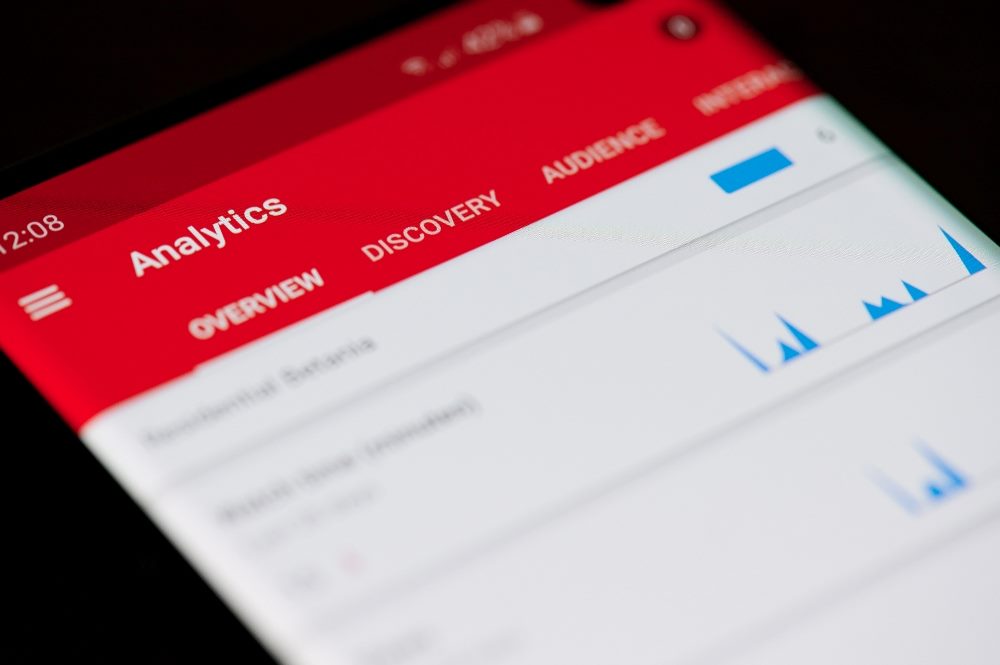 YouTube channel analytics displayed on a smart phone showing YouTube's signature red color.