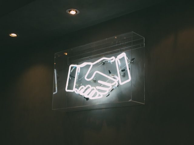 A neon sign of two hands shaking