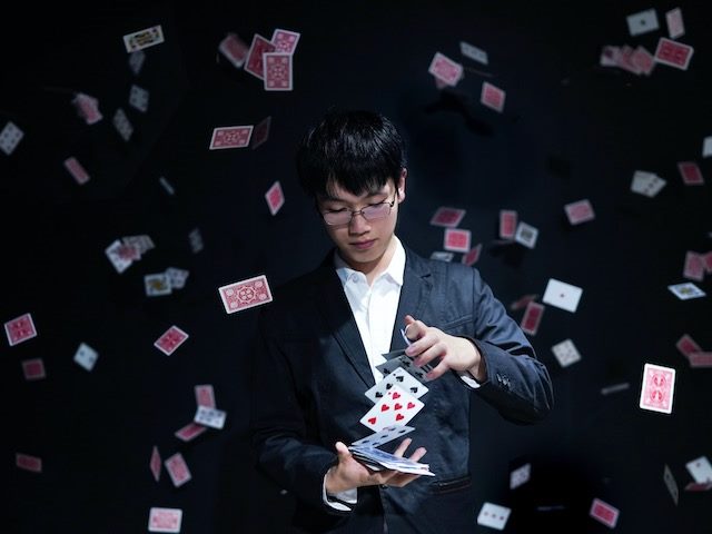 magician in a tuxedo  performing a card trick,  surrounded by cards  flying through the air