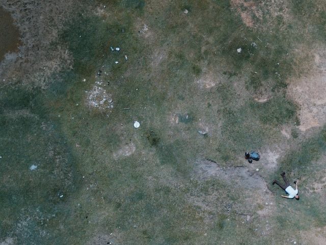 person lying flat on the ground facing up, photographed from above