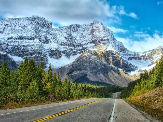 Empty road leading into snowy mountains.