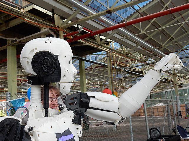 robot lifting its arm with a woman's face visible behind