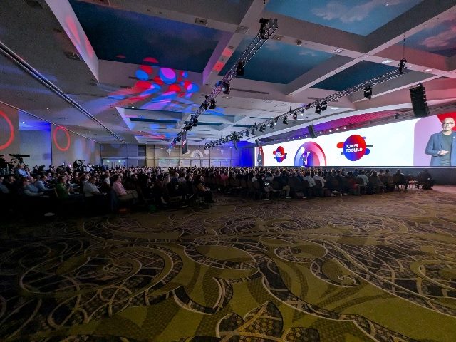Shot from the side of the Sitecore Symposium crowd sitting and listening to Sitecore CEO Dave O'Flanagan's keynote address.