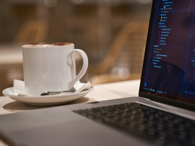 A coffee mug next to a laptop computer.