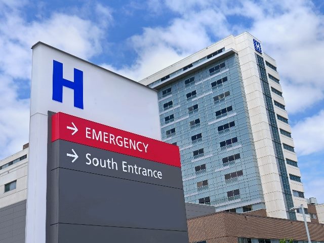 Direction sign with capital letter H for hospital and "emergency" and "south entrance" also written on the sign. AI in healthcare can boost patient experience.