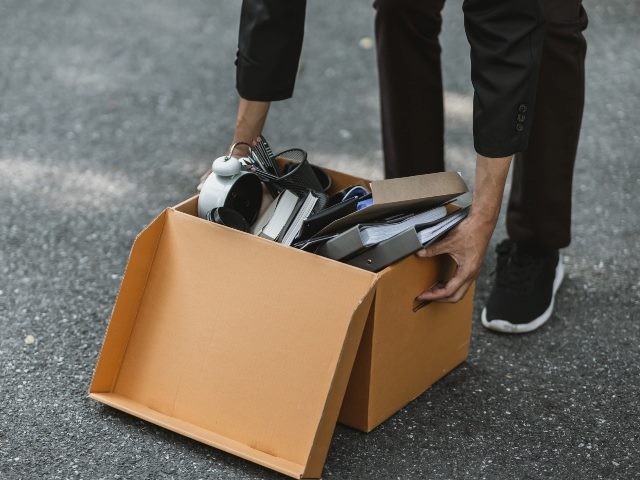 Businessman bends down to reach for a box on the street. 
