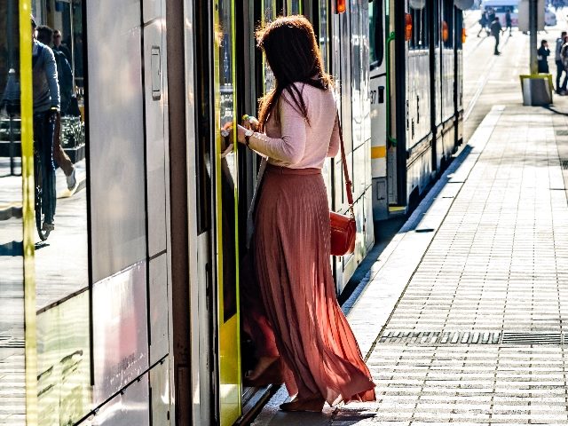 An woman with a long dress gets onboard a Melbourne Australia city tram in the central business district. 