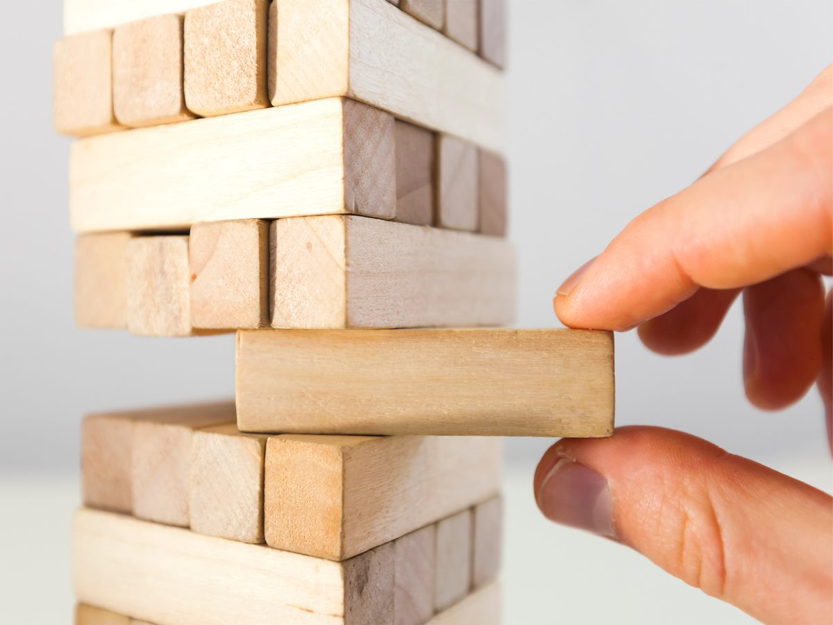 A tower of Jenga blocks, with a hand removing one block