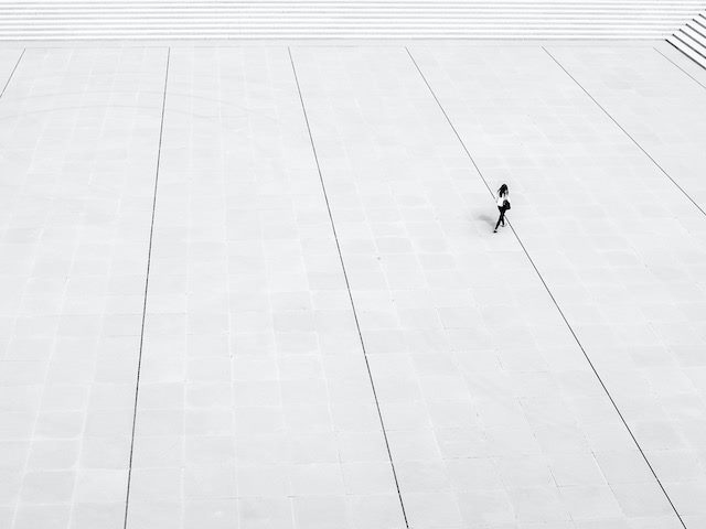 person walking across an empty space towards a stairwell