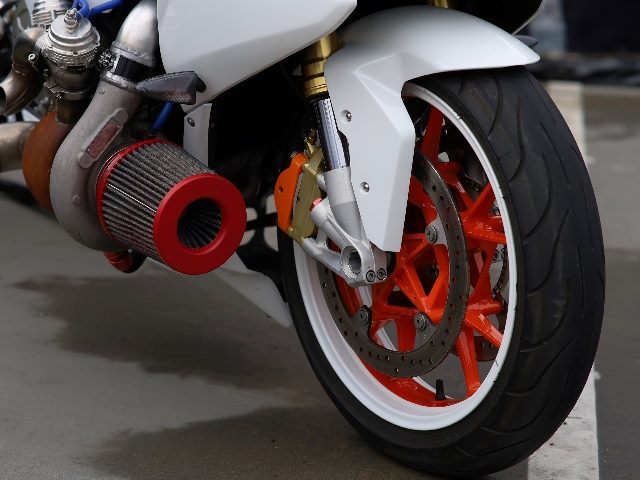 A shot of the back of a turbocharged white motorcycle with red spokes and other red accents, indicating the power of AI in customer experience. 