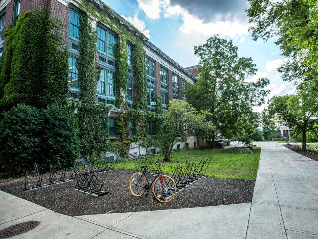 A bike rack by a building on a university campus.