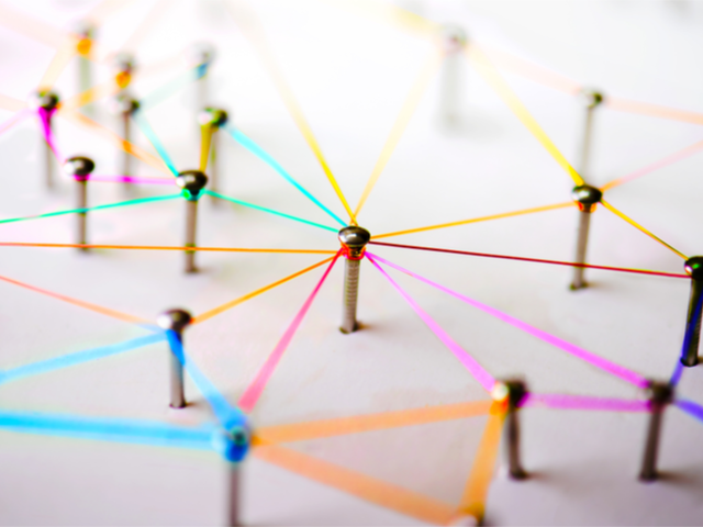 Pins connecting with colored thread strewn across a board, representing data - blockchain ,AI, IoT-concept