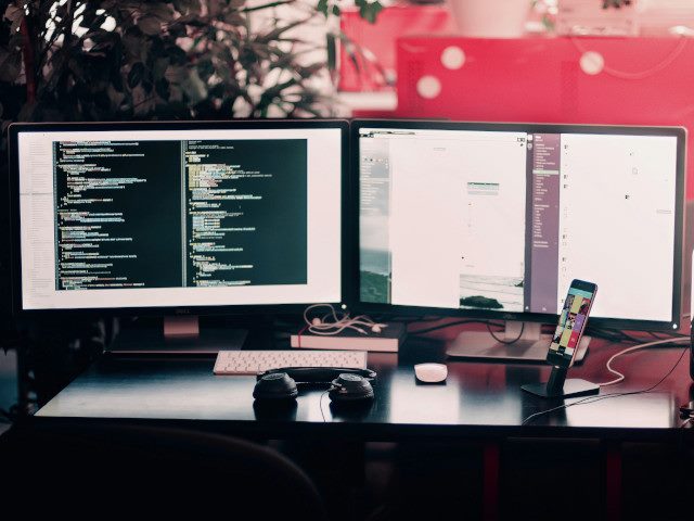 Dual computer monitors on an office desk.