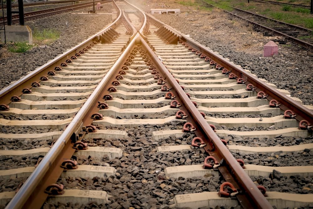 Two railroad paths come together as one with gravel and grass in the sideline and background in piece about AI in customer success.