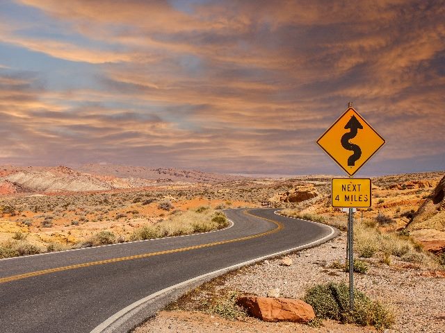 A road sign in the middle of a desert showing curves ahead, symbolizing the road ahead in 2024 for marketing technology trends.