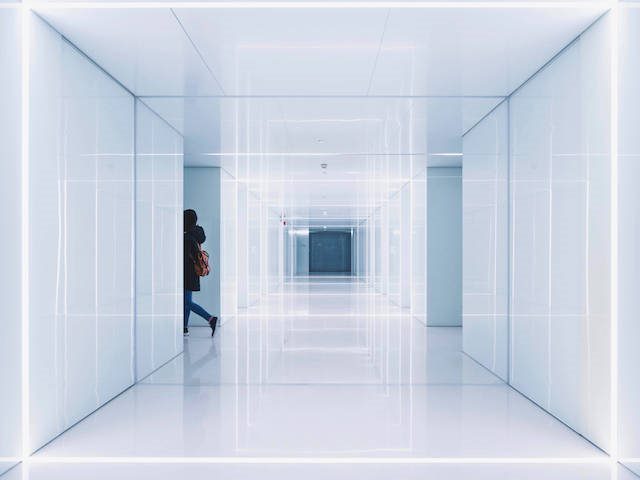 woman disappearing out of view from a bright white corridor