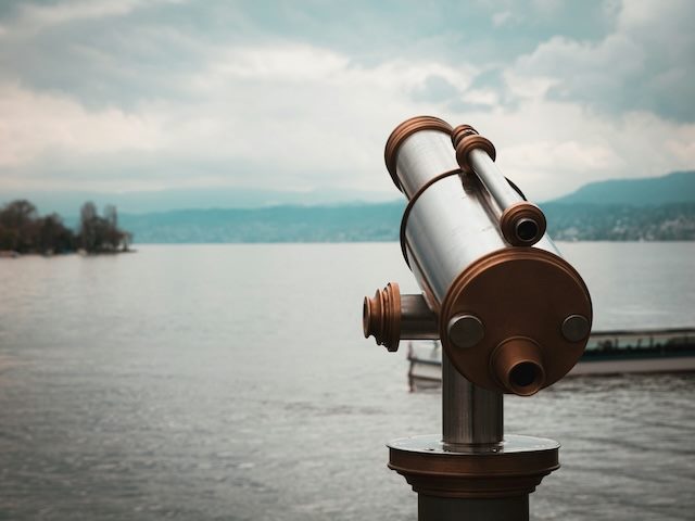 observation binoculars on the shore of a lake surrounded by nature