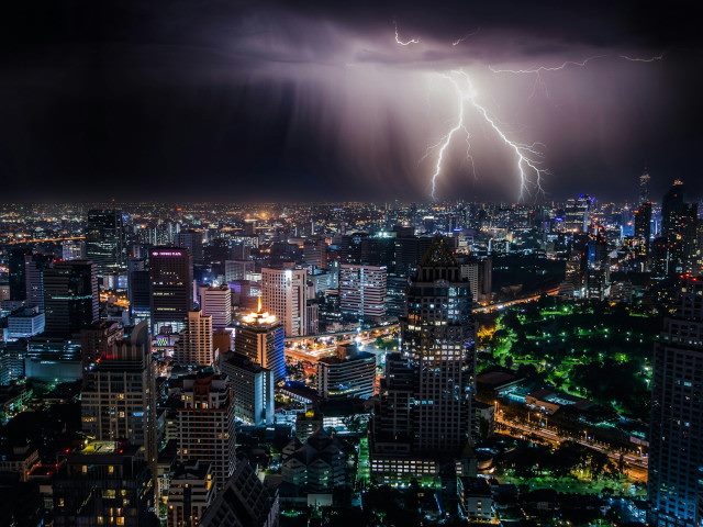 Lightning strikes in the downtown of a city at night.