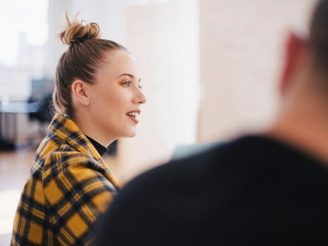 An employee talks with a colleague during a meeting.
