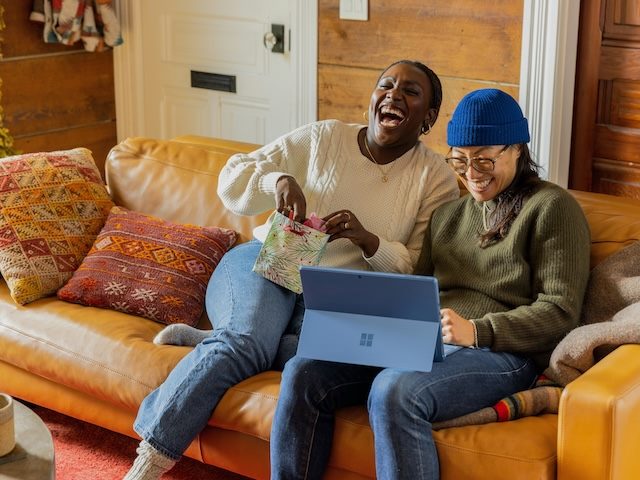 two women sitting on a couch laughing