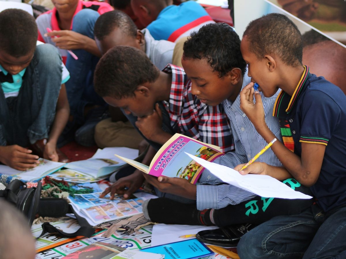 Children sitting down looking over books.