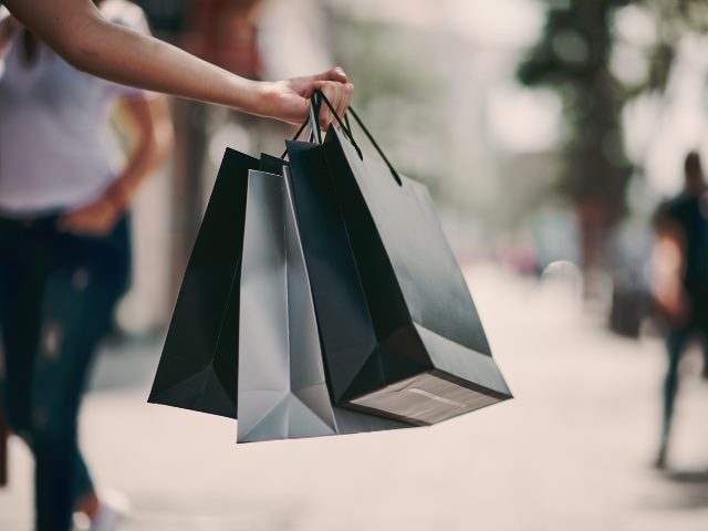 Close up of woman`s hand holding shopping bags while walking on the street