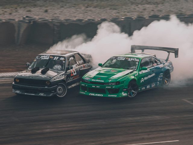 Two race cars turning and burning rubber.