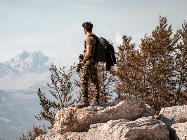 A person with a camera at the top of a cliff