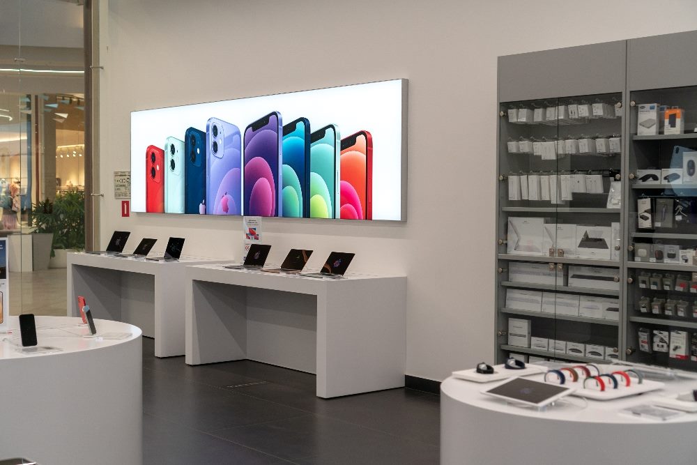 An Apple store with colorful displays of apple products such as Iphone, Macbook, Ipad, Apple logo in piece about Apples Ferret LLM model and customer experience AL.