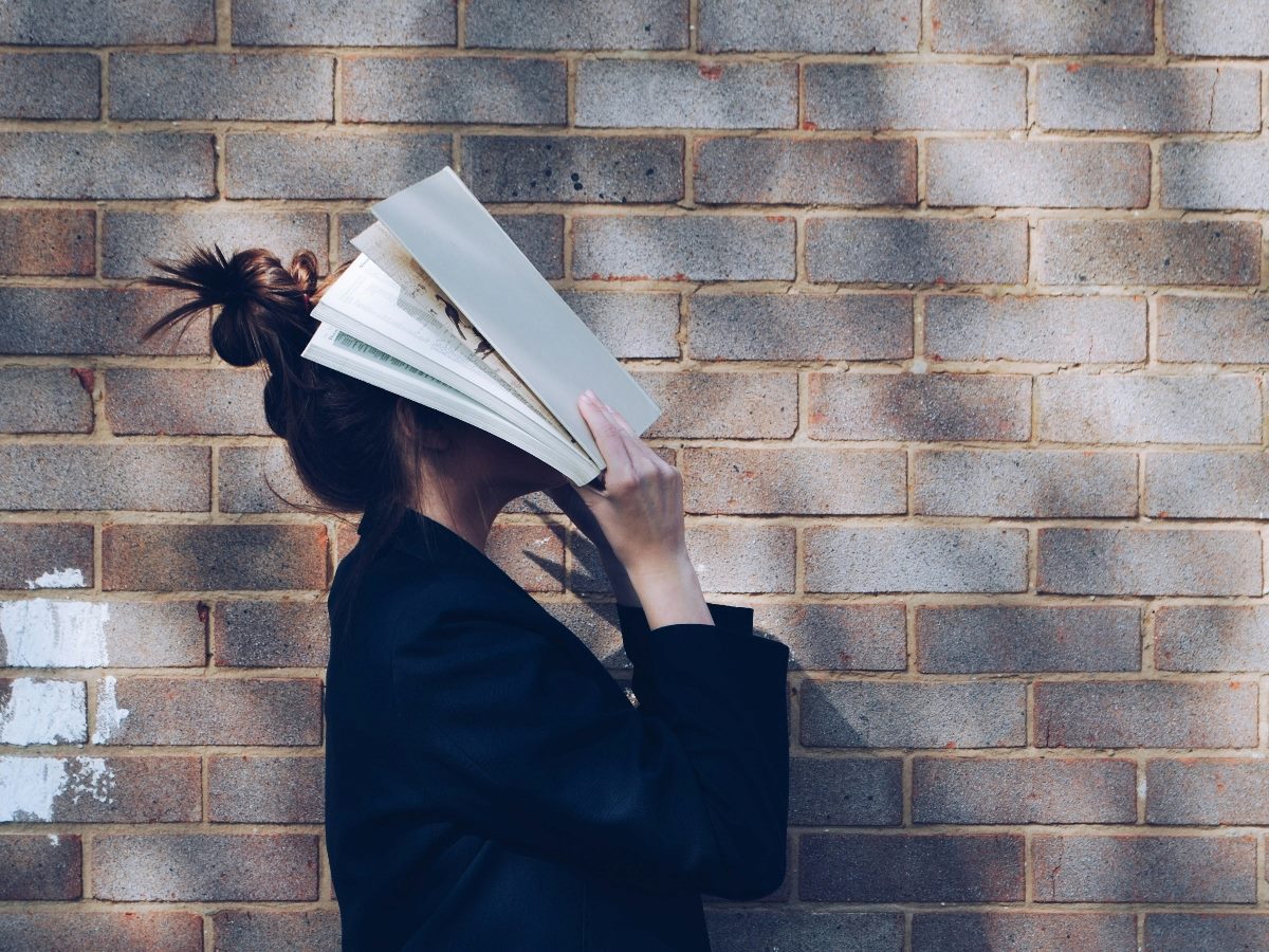 Woman covering her face with a book.