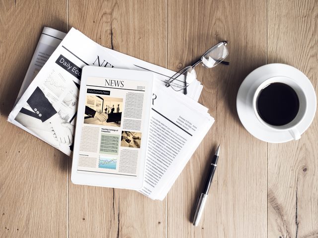 A newspaper with tablet on wooden table