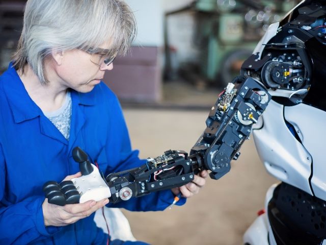 A person examines a robot's arm.