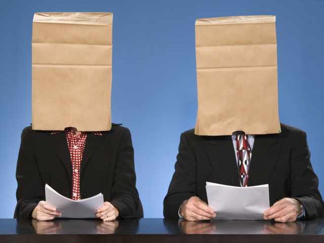Two suited interview candidates holding resumes with bags on their heads - unconscious bias