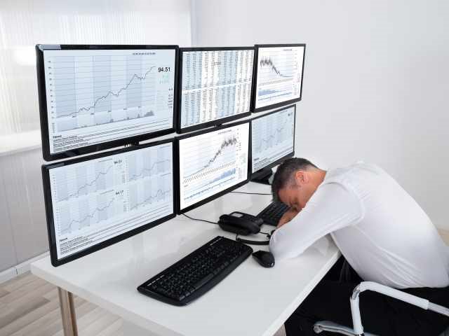 Businessman at desk with multiple monitors filled with data, overwhelmed with all the information his organization is creating