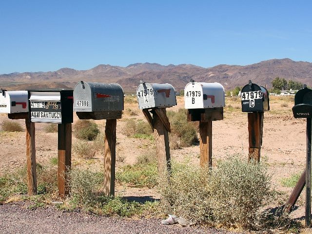 a row of seven mailboxes in a desert climate.