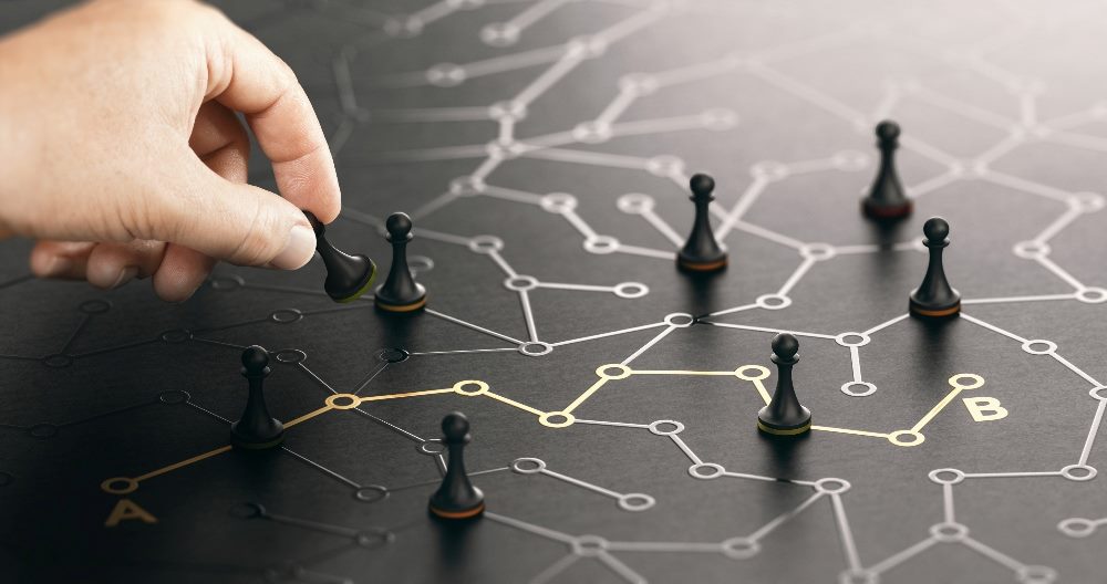 Black game pieces ame pieces set on a black board with a gold line illustrating the shortest rout from point A to point B, illustrating the importance of AI strategy in business.