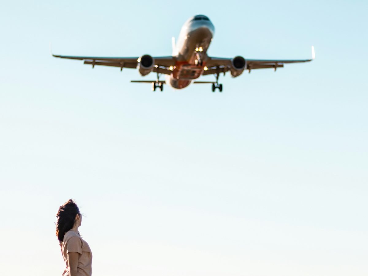 woman on the ground looking up at a plane in the air