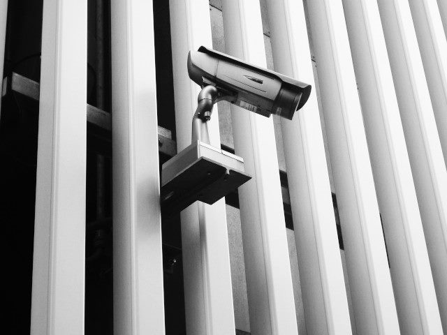 A security camera hangs on the exterior of a building.