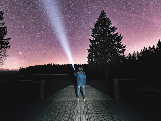 pointing a flashlight at the night sky